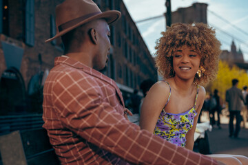 Man and a woman sitting on a bench smiling and flirting