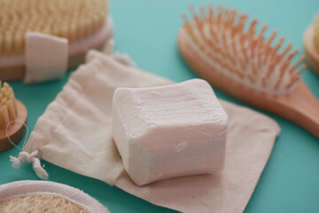 A bar of soap is placed on a cloth beside a brush near to a table