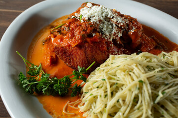 A view of salmon filet with vodka sauce, with a side of angel hair pasta.