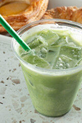 A closeup view of a cold matcha latte in a plastic cup.