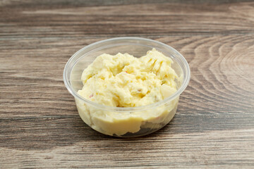 A view of a plastic container of potato salad.