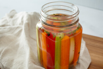 A view of vegetable sticks pickling inside a mason jar.