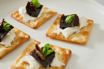 A closeup view of crackers, featuring cream cheese and shoyu marinated kelp.