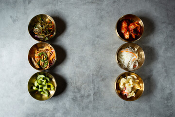 A top down view of a variety of Korean banchan dishes.