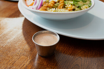 A view of a metal condiment cup of chipotle ranch dressing.