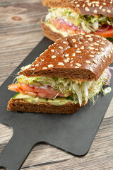 A view of a vegan sandwich on a squaw-roll, cut in half.