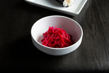 A closeup view of a condiment cup of shredded daikon radish.