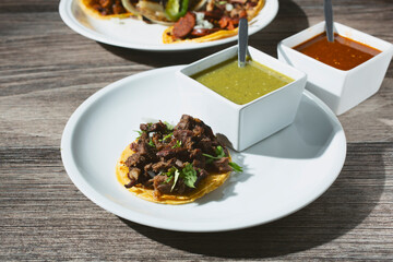 A view of a carne asada taco, with some salsas.