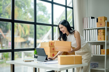 A woman is standing in front of a table with a laptop and a box