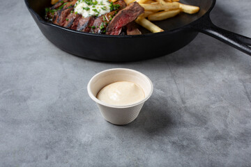 A view of a paper condiment cup of aioli.