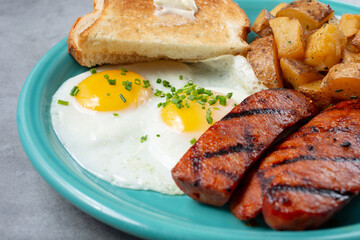 A view of a breakfast plate featuring fried eggs and linguica sausage.