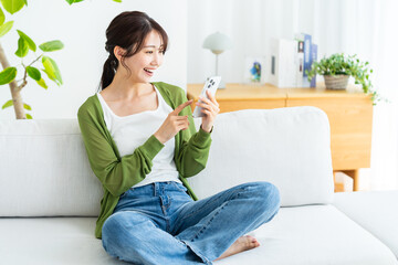 部屋でスマホを操作する若い女性