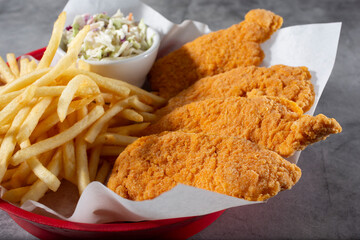 A view of a basket of chicken tenders and French fries.