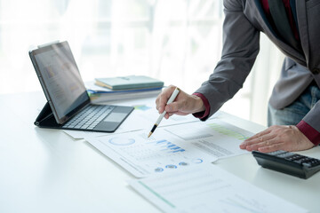 A man is sitting at a desk with a laptop and a pen