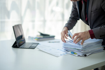 A man is sitting at a desk with a pile of papers in front of him