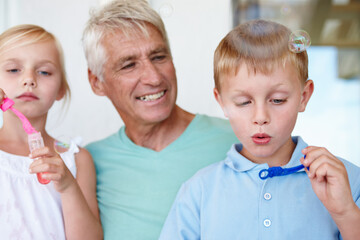 Grandfather, kids and bubbles with bonding in home for child development with retirement. Grandpa,...