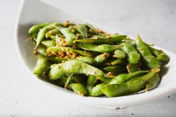A closeup view of a plate of garlic edamame.