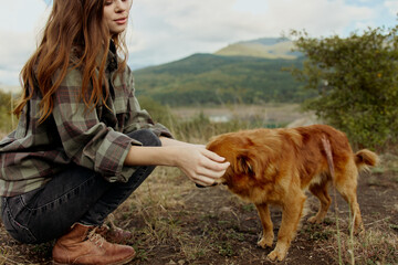 Serene young woman enjoying the company of a friendly dog in a scenic mountain field landscape