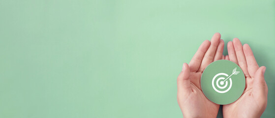 Hand holding target paper cut, achieve on point, sustianable challenge goal, business objective...
