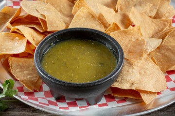 A closeup view of a plate of chips and salsa verde.