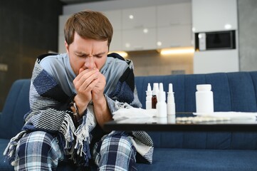 Sick man on sofa at home in living room. man feeling sick with cold and fever at home, ill with flu...