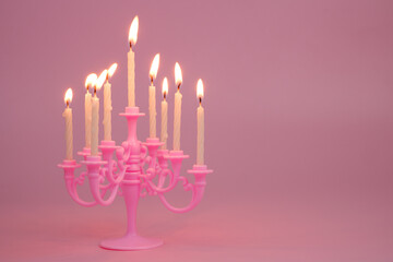 Fototapeta premium Candelabra with burning candles on pink background. Copy space for text. 