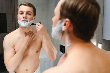 Confident guy using shaver in bathroom