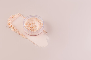Open cosmetic jar with delicate loose powder on pastel background with powder swatch. A copy space. Product advertising.