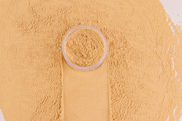 A cosmetic jar with loose powder in a beige tone stands on the sample with a trace of a jar and a background of loose powder. decorative cosmetics