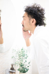 Middle-aged Japanese man with beard looking in the mirror Hair removal and morning image Men's...