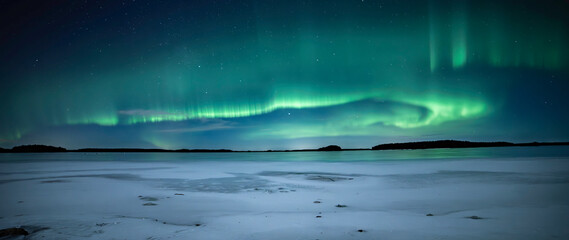 Northern lights dancing over frozen lake in Farnebofjarden national park in north of Sweden