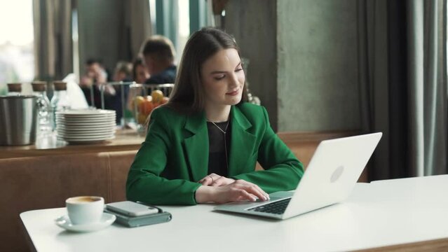 lovely woman in a green jacket starts to dance while sitting at a table in a restaurant with a good mood and a smile.