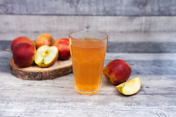 Glass of apple juice and apple slice on wooden table.