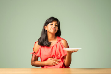 Indian asian small girl child saying no thanks to empty food plate