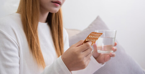 A young woman with a birth control pills reads instructions on how to use them correctly.