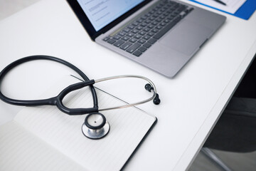 Stethoscope, laptop and desk for healthcare background, medical research and hospital services or...