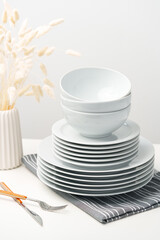 Stylish table setting with white dishware on white tablecloth