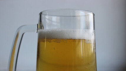 Top part of glass with handle filled of craft brown ale covered with foam closeup view

