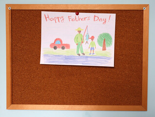 Father's Day card drawn by child. Attached with button to cork board. Blue wall. Colored pencil....
