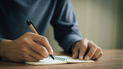 businessman working at work table,home office desk background, checklist writing planning investigate enthusiastic concept. Male hand taking notes on the notepad. 