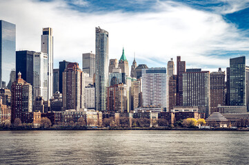 Obraz premium Witness the awe-inspiring panorama of New York City from the tranquil waters of the Hudson River. Iconic skyscrapers pierce the twilight sky.