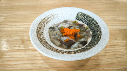japanese food Octopus Tako Wasabi served in a bowl isolated on wooden table top viewม Close up Tako wasabi (Spicy Squid salad)