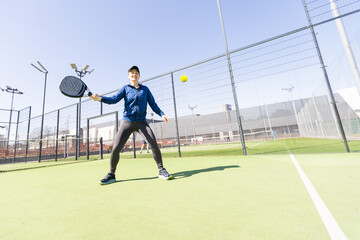 Determined sporty young woman playing padel in court