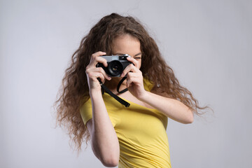 Portrait of a gorgeous teenage girl with curly hair holding camera. Studio shot, white background with copy space