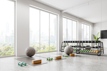 Yoga room interior with dumbbell rack and punching bag, tv and window