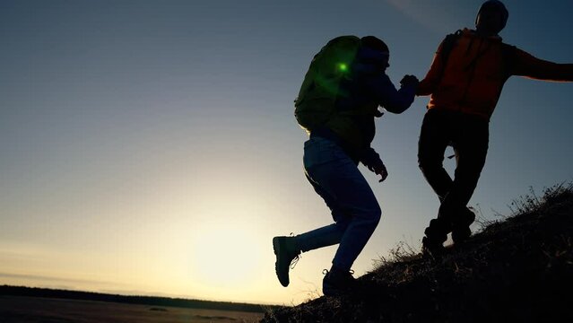 Successful business concept. man and woman together in mountains at sunset. teamwork. business and achieving goal together. success and help in the team. helping hand to achieve goal. joint success