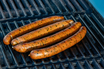 Four spiced sausages heated on gas grill