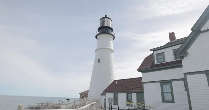 Beautiful up close view of the Portland Maine Head Light light house during a beautiful spring day with waves rolling into the rocky shore in 4k.