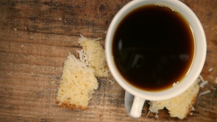 An overhead shot of a cup of hot coffee and cake slices on the table. An espresso coffee cup ready...