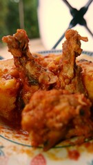 A close-up shot of a hot polenta plate with cooked chicken thighs and onion sauce by the window. A hot polenta bowl (cooked corn meal). Boiled chicken legs. Cooked polenta. Chicken drumsticks. 